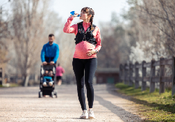A pregnent young lady drinking water during walking