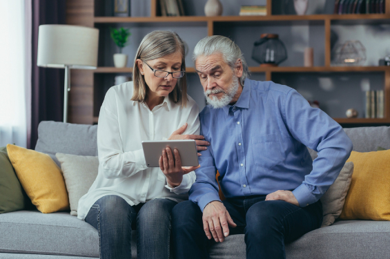 An old couple busey with their device